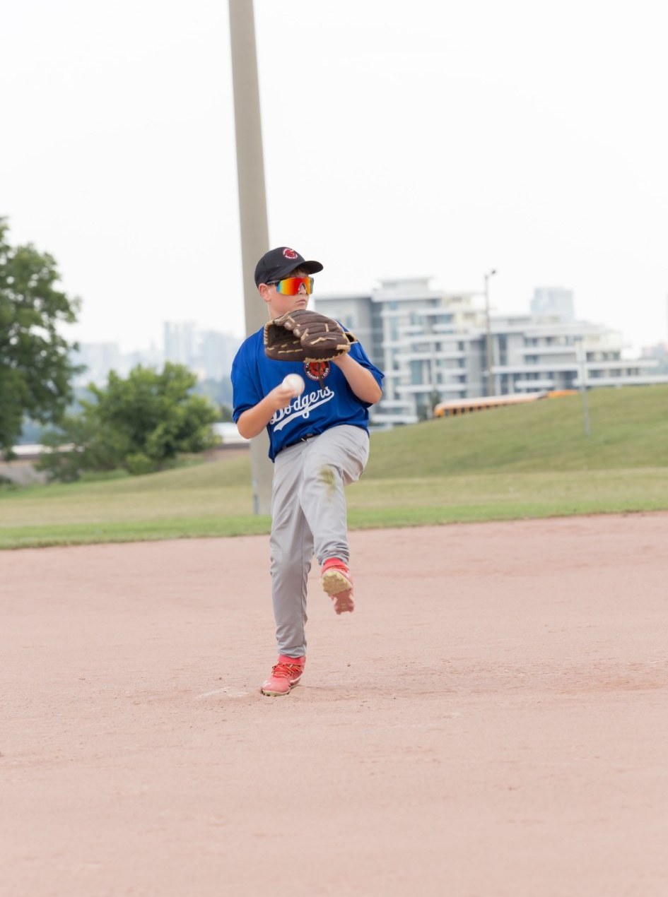 Young pitcher striding toward the plate, ball in hand, real game